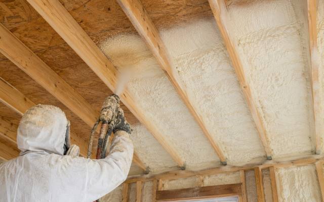 Installer spraying foam on the underside of a roof deck
